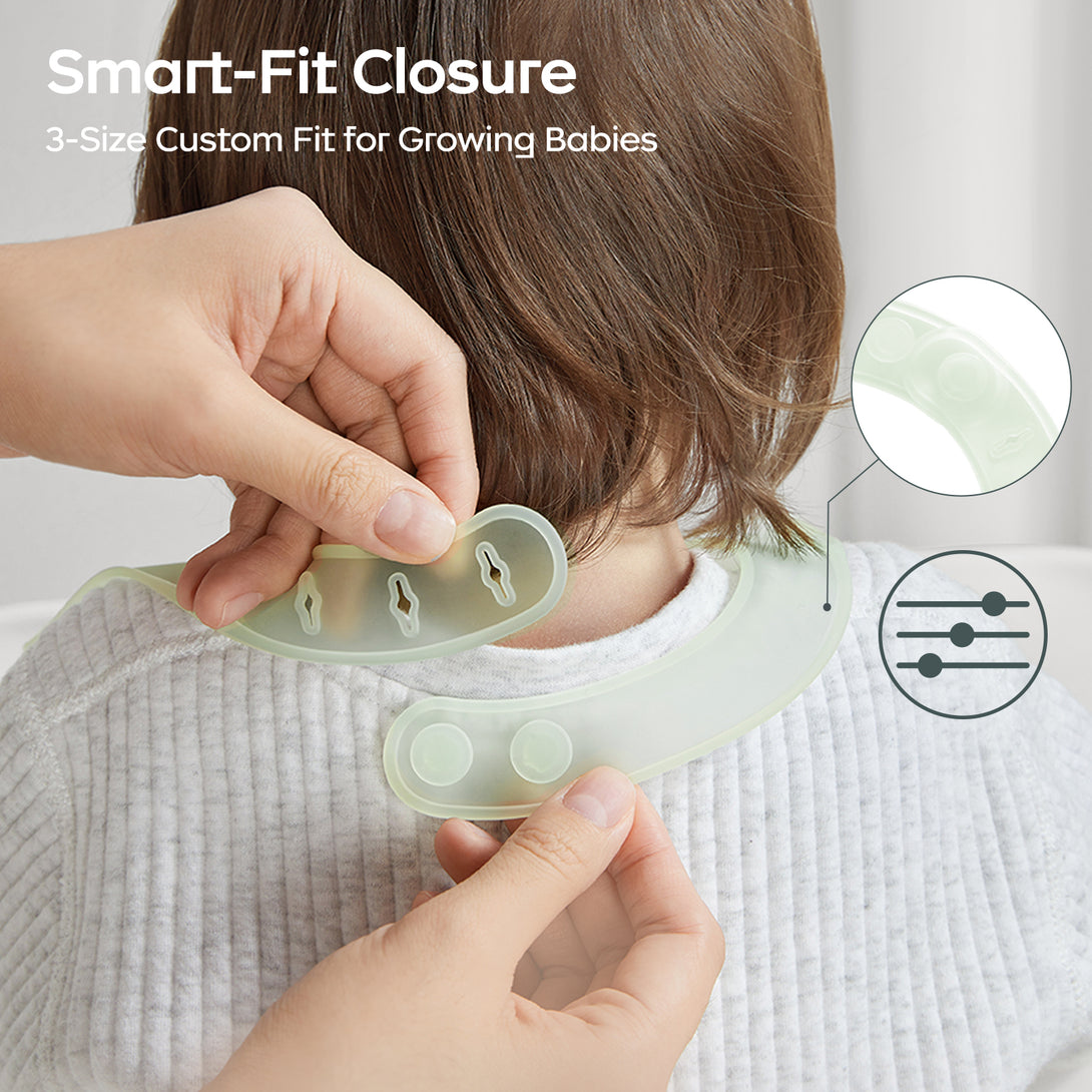 Parent adjusting strap length on baby's feeding bib while child wears it.