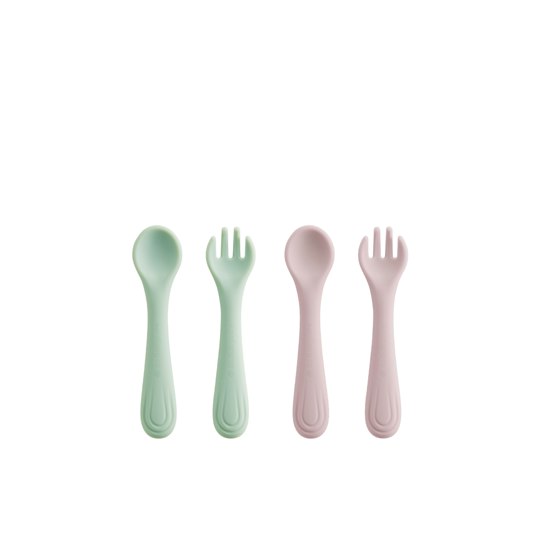 Two silicone fork and spoon sets, one pink and one green, arranged on a white background (four pieces total).