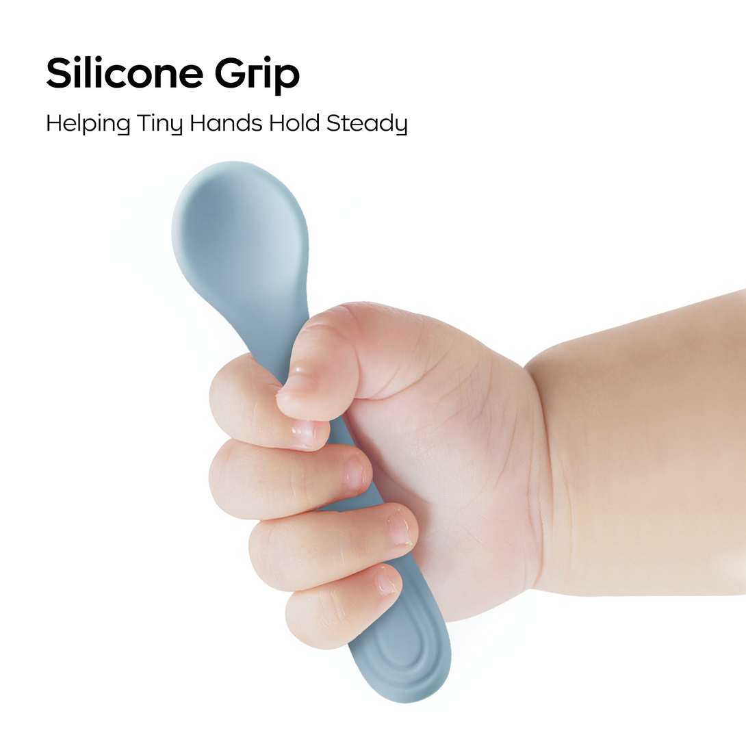 A child's hand holding a blue silicone spoon against a white background.