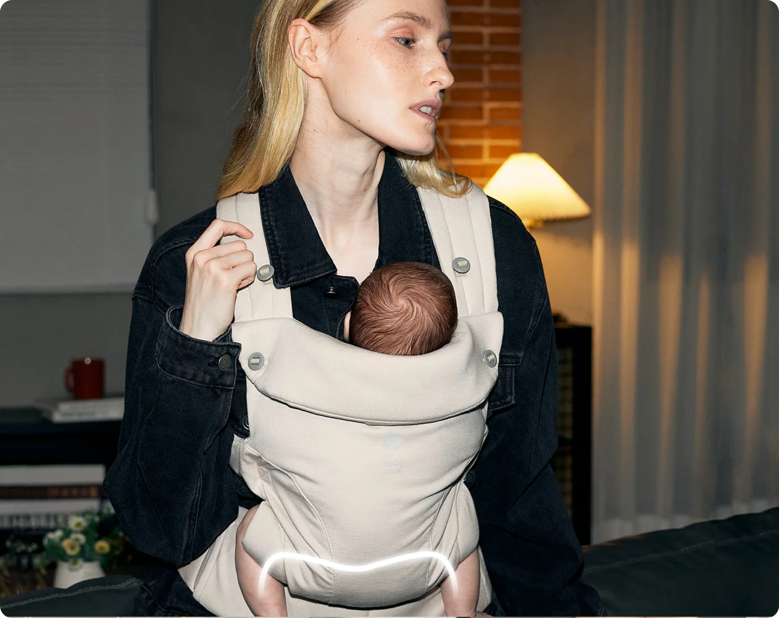 Mother wearing the CocoonGo Baby Carrier in Light Beige with her baby supported in a front inward-facing position.